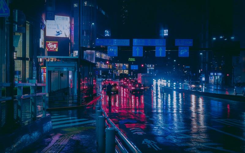 A city street at night, lit by illuminated signs